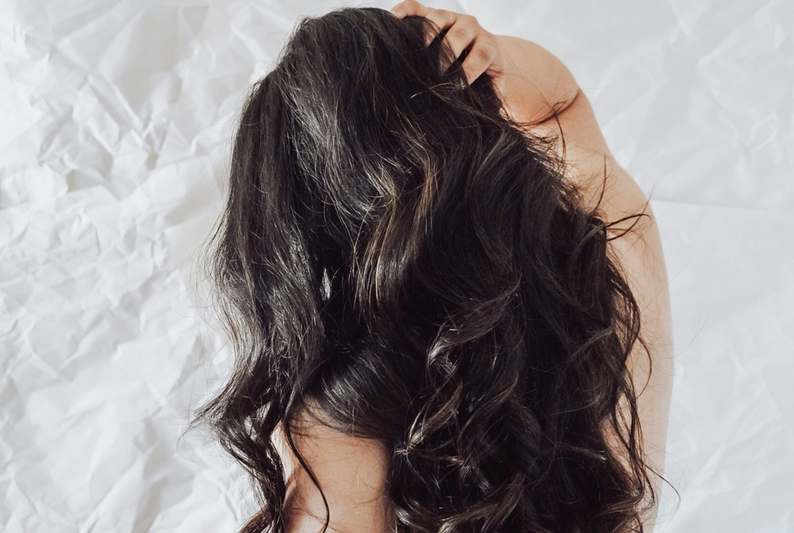 Close-up of hands gently massaging scalp with hair clip nearby